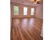 Bright living room featuring wood-look flooring and three large windows at 25012 Chipshot Ct, Sorrento, FL 32776
