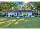 Charming one-story home featuring a well-maintained lawn, mature trees, and a welcoming entrance with a blue door at 31024 Prestwick Ave, Sorrento, FL 32776