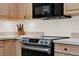 Close-up of a kitchen featuring stainless steel oven and stovetop with light wood cabinets and stone countertops at 31024 Prestwick Ave, Sorrento, FL 32776