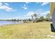 Expansive grassy backyard leading to a serene lake with clear blue sky and scattered clouds at 330 Osprey Lakes Cir, Chuluota, FL 32766