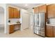 Bright kitchen featuring stainless steel refrigerator, wood cabinets, and built-in desk area at 330 Osprey Lakes Cir, Chuluota, FL 32766