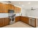 Well-lit kitchen with stainless steel appliances, quartz countertops, and warm wood cabinetry at 330 Osprey Lakes Cir, Chuluota, FL 32766