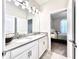 Bright bathroom featuring a double vanity with white cabinets and gray countertop, next to the bedroom entrance at 4562 Tribute Trl, Kissimmee, FL 34746