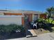 Orange townhome with a sidewalk leading up to the front door with lush greenery and lawn at 46 Silver Park Cir, Kissimmee, FL 34743