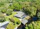 An aerial view of the home shows lush landscaping, a screened pool, and a private boat dock on the water at 5370 Whispering Pine Cir, St Cloud, FL 34771