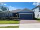 Charming single-story home with blue exterior, brick driveway, manicured lawn, and lush landscaping at 5526 Bonn Way, St Cloud, FL 34771