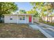 Cozy single-story home featuring a red front door, covered porch, and a charming landscape at 616 Conroy St, Orlando, FL 32805