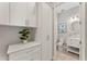 Hallway with white cabinets, countertops and plant, leading to powder room with toilet and vanity at 7131 Desert Mandarin St, Winter Garden, FL 34787