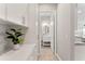 Hallway with white cabinets and countertops leading to a bathroom with white vanity and oval mirror at 7131 Desert Mandarin St, Winter Garden, FL 34787