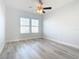 Sun-lit bedroom features gray wood floors, a ceiling fan, and white trim at 869 Taramundi Dr, Oviedo, FL 32765