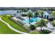 Scenic aerial view of a community pool area, playground, and clubhouse amidst lush greenery at 8872 Bismarck Palm Dr, Winter Garden, FL 34787