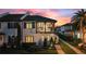 Charming two-story home with a private balcony, complemented by lush landscaping and a colorful twilight sky at 8872 Bismarck Palm Dr, Winter Garden, FL 34787