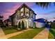 Stunning two story exterior with balcony, manicured landscaping and a beautiful sunset sky above the residence at 8872 Bismarck Palm Dr, Winter Garden, FL 34787