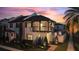 Elegant two-story home with a cozy balcony and meticulously landscaped front yard against a striking sunset backdrop at 8872 Bismarck Palm Dr, Winter Garden, FL 34787