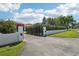 Gated driveway entrance featuring white pillars and manicured hedges, enhancing privacy and curb appeal at 950 N Lake Otis Dr, Winter Haven, FL 33880