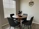 Cozy dining area featuring a round wooden table, four modern chairs, and natural light from the window at 11562 Westwood Blvd # 934, Orlando, FL 32821