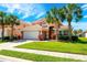 Well-maintained home with lush landscaping, mature palm trees, and a two-car garage at 217 Sevilla Ave, Davenport, FL 33897