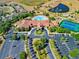 Aerial view of a clubhouse with a pool, tennis courts, fountains, and a parking lot surrounded by trees and landscaping at 3492 La Jolla Dr, Clermont, FL 34711