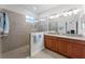 Luxurious primary bathroom featuring a double sink vanity with wood cabinets and a tiled shower with glass door at 3492 La Jolla Dr, Clermont, FL 34711