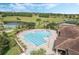 Aerial view of the zero entry community pool, with a jacuzzi, sun loungers, and a view of the green space and lake at 3492 La Jolla Dr, Clermont, FL 34711