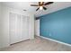 Bedroom with a ceiling fan, tile floor, closet with doors and a dark teal accent wall at 412 Short Dr, Poinciana, FL 34759