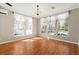 Bright living room with hardwood floors, multiple windows with sheer curtains, and elegant chandelier lighting at 780 Old Mount Dora Rd, Eustis, FL 32726