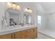 Bright bathroom featuring a double vanity, modern lighting fixtures, and a separate shower with neutral tiling at 822 Swaying Palm Dr, Apopka, FL 32712