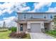 Charming two-story home with an attached garage, manicured lawn, and stone veneer accents under a sunny, partly cloudy sky at 844 Driving Range Ct, Reunion, FL 34747