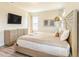 Bedroom with neutral tones, decorative headboard, dresser, and large wall-mounted TV at 844 Driving Range Ct, Reunion, FL 34747