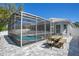 Outdoor dining set on a paved patio next to a screened pool enclosure and lush foliage at 908 Jade Forest Ave, Orlando, FL 32828