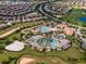Aerial view of a community clubhouse featuring multiple pools, sand volleyball, and lush landscaping at 1565 Mulligan Blvd, Davenport, FL 33896