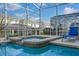 Relaxing screened-in pool and spa featuring tiled accents and beautiful outdoor views at 1565 Mulligan Blvd, Davenport, FL 33896