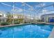 Expansive screened-in pool reflecting the sky, with a spa and comfortable seating area at 1565 Mulligan Blvd, Davenport, FL 33896