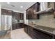 Well-equipped kitchen with stainless steel appliances, dark cabinetry, and gray backsplash at 16003 Tangerine Blossom Way, Winter Garden, FL 34787