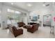Spacious living room with brown leather sofas, large windows, and neutral tile flooring, perfect for entertaining at 16003 Tangerine Blossom Way, Winter Garden, FL 34787