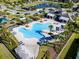 Aerial view of a large community pool and clubhouse, surrounded by lush landscaping and lounge seating at 16003 Tangerine Blossom Way, Winter Garden, FL 34787