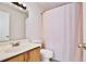 Bathroom with wooden vanity and a shower featuring a textured pink curtain, exuding a functional design at 209 Roman Ct, Deltona, FL 32738