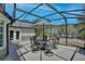 Screened patio featuring an outdoor dining set, providing a comfortable space for enjoying the tranquil lake view at 209 Roman Ct, Deltona, FL 32738