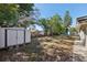 A spacious backyard featuring a storage shed, mature trees, and a mix of grass and sandy areas under a sunny sky at 2318 Vincent Rd, Orlando, FL 32817