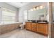 Bright bathroom features double sinks, granite countertop, soaker tub under a window, and tiled floors at 2361 Baker Ave, Orlando, FL 32833