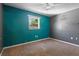 A compact bedroom featuring neutral carpet, teal accent wall with a window, and overhead fan at 241 S Marydell Ave, Deland, FL 32720