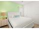 Bright bedroom featuring a king bed, a nightstand, a window with blinds, and a pastel green accent wall at 2967 Latitude Ln, Kissimmee, FL 34747