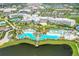 Aerial view of a lakefront resort with pools, lounge chairs, cabanas, tiki bar, palms, and water access at 3083 Pirate Way, Kissimmee, FL 34747