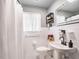 Clean bathroom featuring white tiles, a pedestal sink, a modern black faucet, and a shower with striped curtain at 392 W Minnehaha Ave, Clermont, FL 34711
