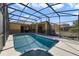 Sparkling pool with a jacuzzi inside a screened-in enclosure and a sun lounger on the pool deck at 419 Coventry Rd, Davenport, FL 33897