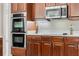 Close-up of built in stainless steel oven and microwave with dark wood cabinetry and white countertops at 504 Sonata Ct, Winter Springs, FL 32708