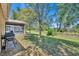 Spacious backyard featuring lush green grass, mature trees, and a screened-in patio at 5910 Windsong Oak Dr, Leesburg, FL 34748
