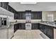 Contemporary kitchen with stainless steel appliances, dark cabinetry, and tile flooring at 5910 Windsong Oak Dr, Leesburg, FL 34748
