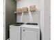 Functional laundry room with white washer and dryer, plus shelving for storage at 6038 Tree Crossing Ln, St Cloud, FL 34771