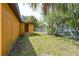 Exterior of yellow house and yard with a lush green lawn, trees, and a fence at 612 Kensington St, Eustis, FL 32726